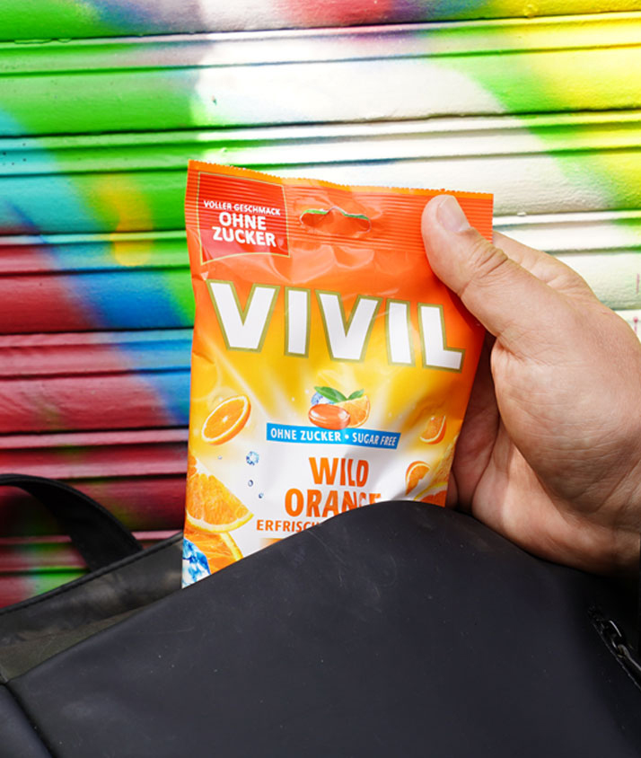 Orangenbonbon wird aus Rucksack gezogen Orangenbonbon wird aus Rucksack gezogen